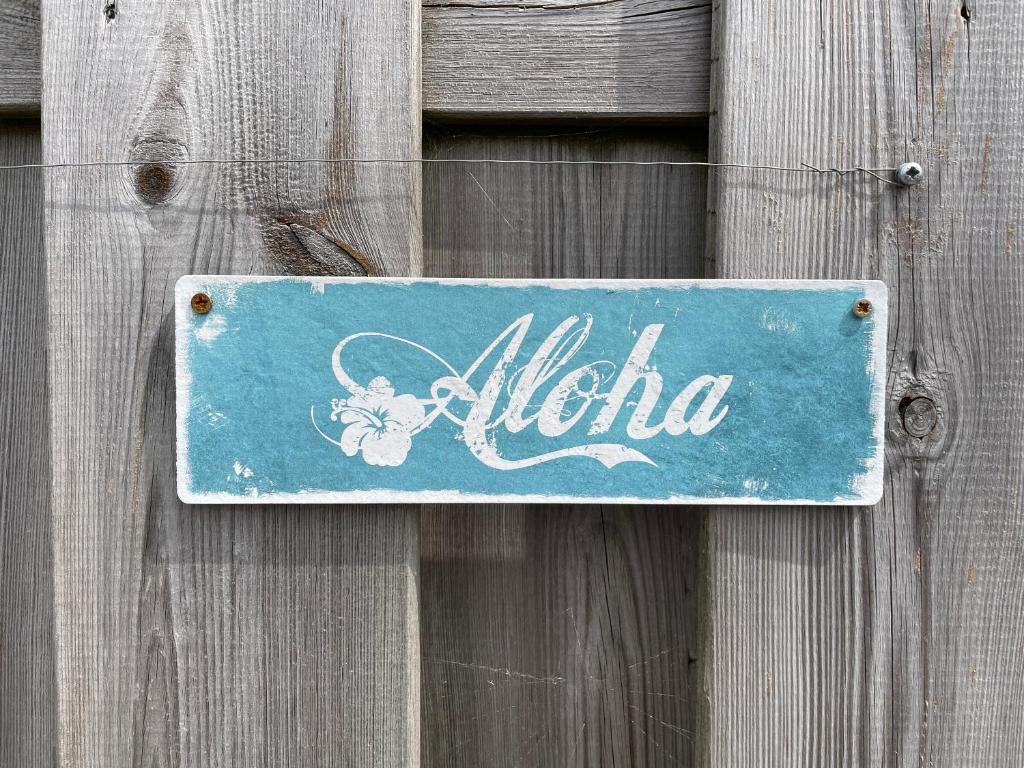 una señal azul en una puerta de madera con la palabra aloha en Aloha-Olmenduin, en Serooskerke