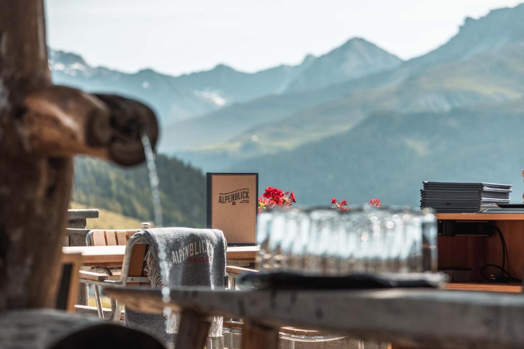 a table with glasses on it with mountains in the background at Alpenblick Bergrestaurant & Hotel in Arosa