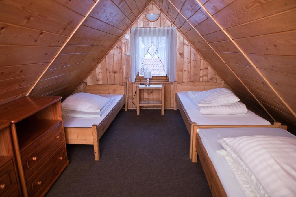 a room with two beds in a wooden cabin at Domki z jacuzzi Pasja I in Mizerna