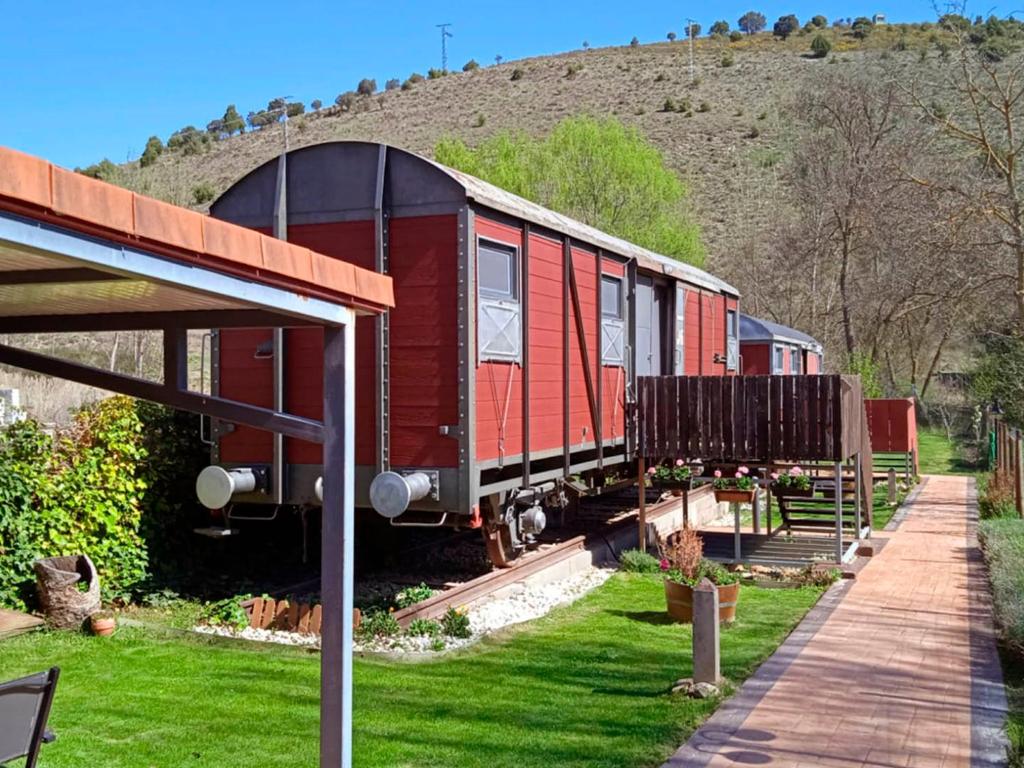 Baides的住宿－El Vagón de Baides，坐在院子里的铁轨上的红色火车