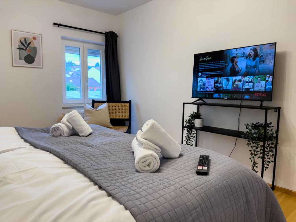 a bedroom with a bed with towels and a flat screen tv at STYLISCHE ZENTRALE WOHNUNG MIT KÜCHE UND PARKPLATZ IN SEITENSTRAẞE in Deggendorf