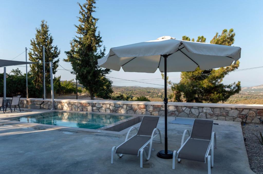 een zwembad met 2 stoelen en een parasol naast een zwembad bij Villa Iliousa Grand in Psinthos