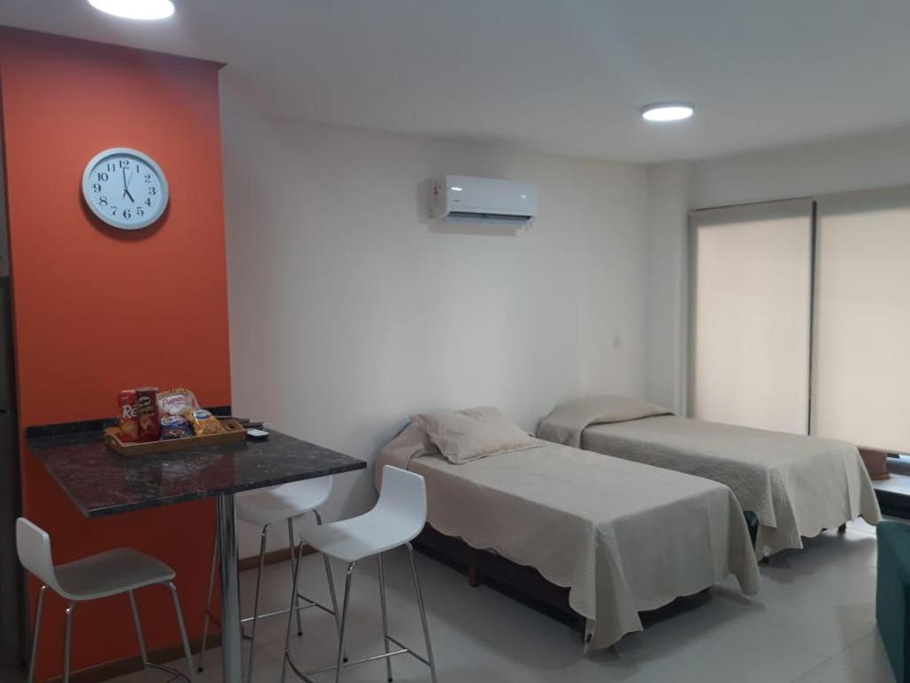 Zimmer mit 2 Betten, einem Tisch und einer Uhr in der Unterkunft Departamento en Recoleta excelente in Buenos Aires