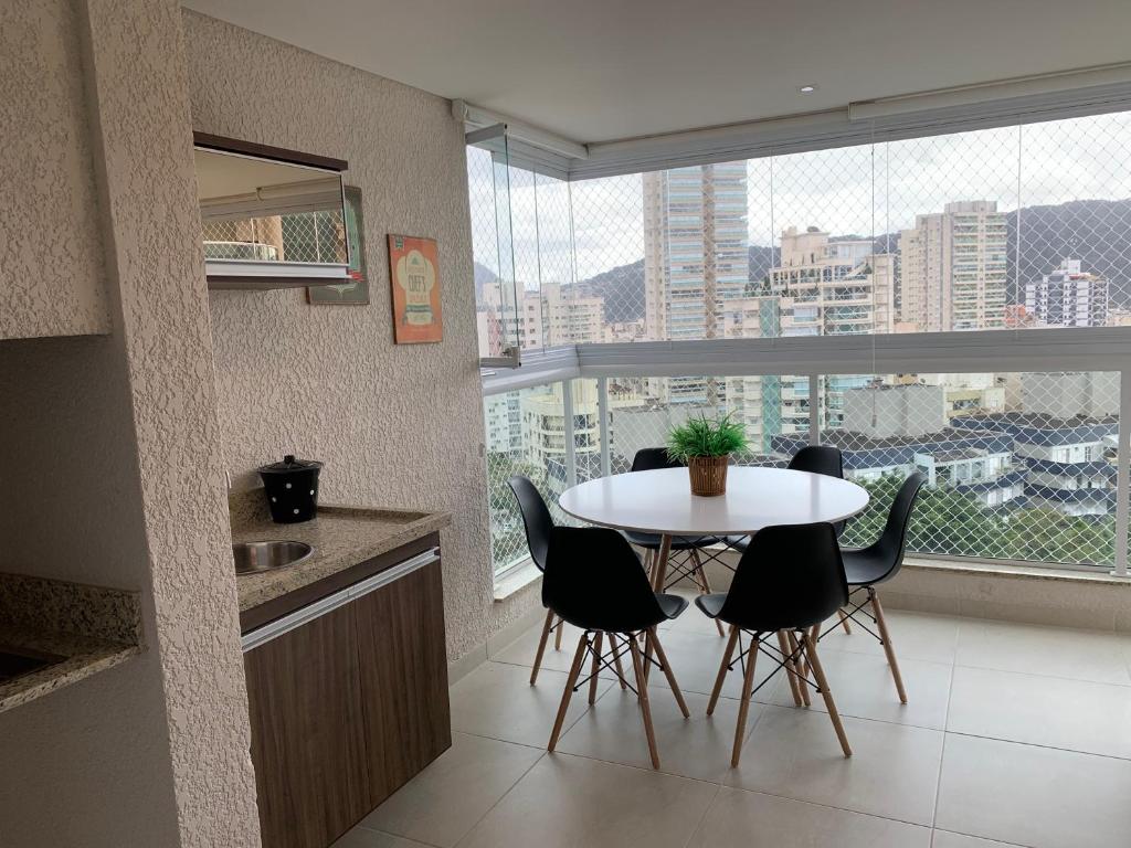 una cucina con tavolo e sedie di fronte a una finestra di Apartamento Alto Padrão / prédio com piscina e quadra. a Guarujá