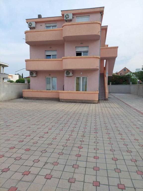 a pink house with a tile floor in front of it at Fikret-apartmani Velika plaža in Ulcinj