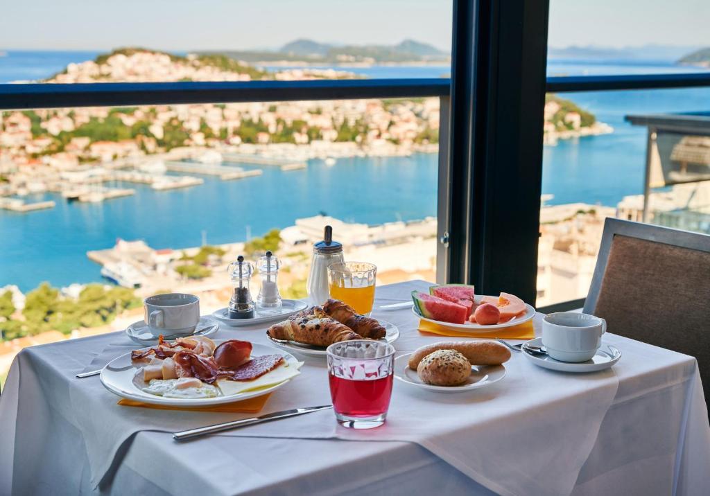 a table with plates of food and a view of the ocean at Hotel Adria in Dubrovnik