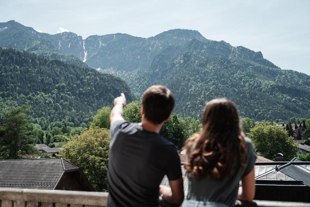Ein Mann und eine Frau stehen auf einem Balkon mit Bergblick in der Unterkunft Hotel Vötterl in Grossgmain