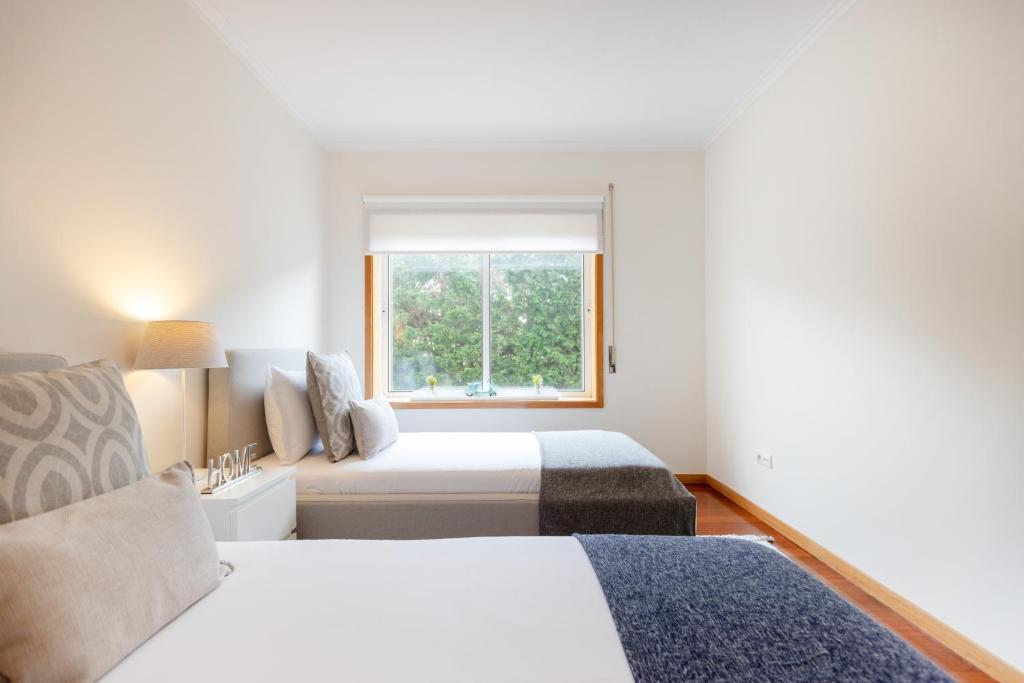 a bedroom with two beds and a window at São Félix Seaside Oasis in São Félix da Marinha
