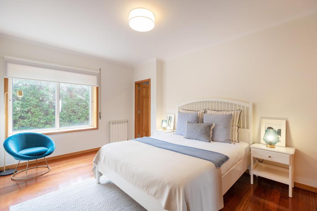 a bedroom with a large bed and a blue chair at São Félix Seaside Oasis in São Félix da Marinha