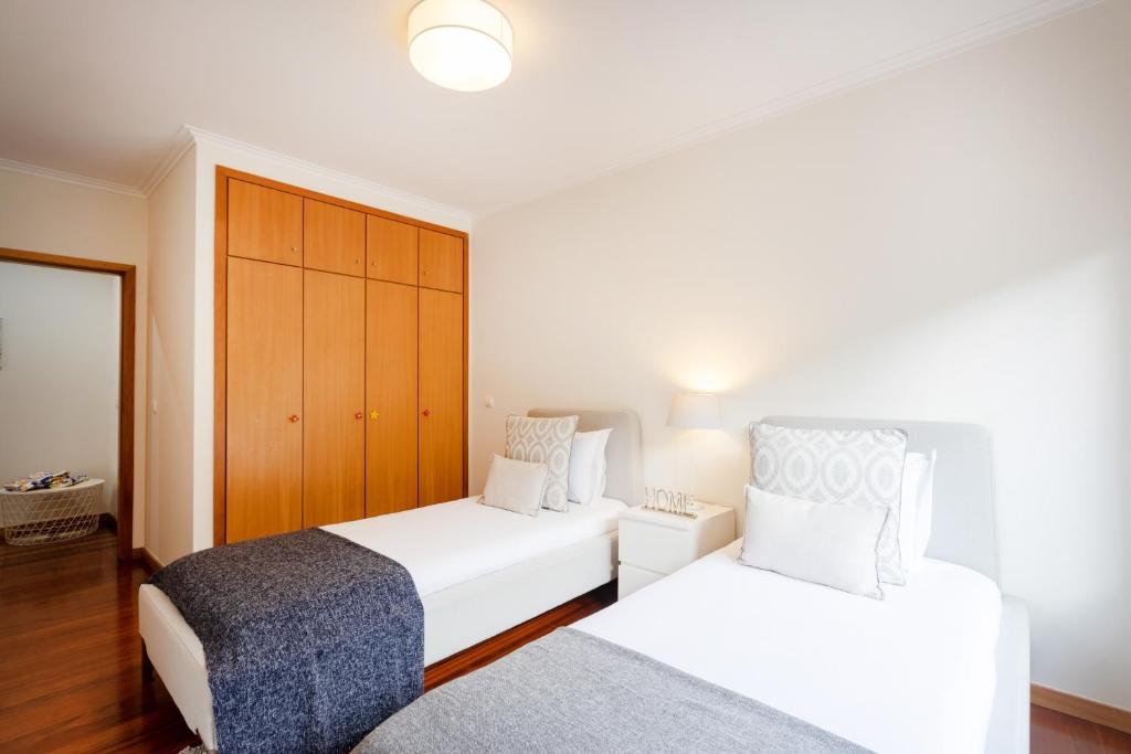 a bedroom with two beds and a cabinet at São Félix Seaside Oasis in São Félix da Marinha