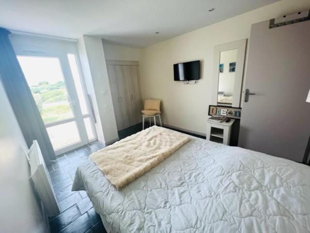 Un dormitorio con una gran cama blanca y una ventana en REPOS SUR L'EAU, en Guidel