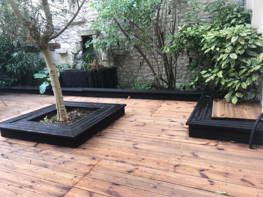 a courtyard with a tree in a black planter at La campagne dans l'Ocean à LA ROCHELLE les pieds dans la grange in Croix-Chapeau