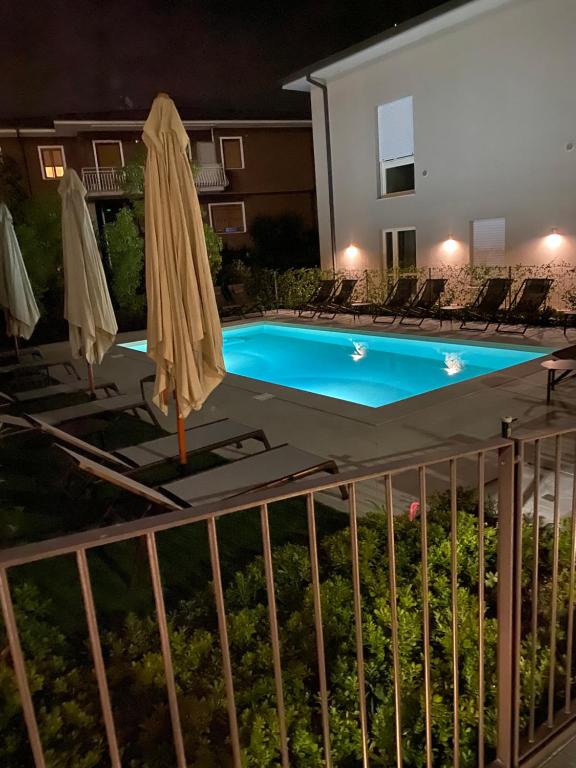 a pool at night with umbrellas and chairs at Hotel B&B il Mosaico in Sirmione