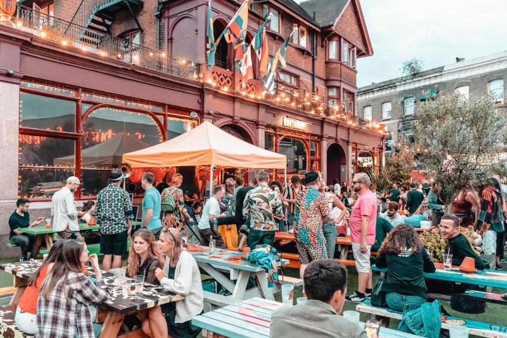 a group of people sitting at tables outside a building at Hootananny Hostel in London