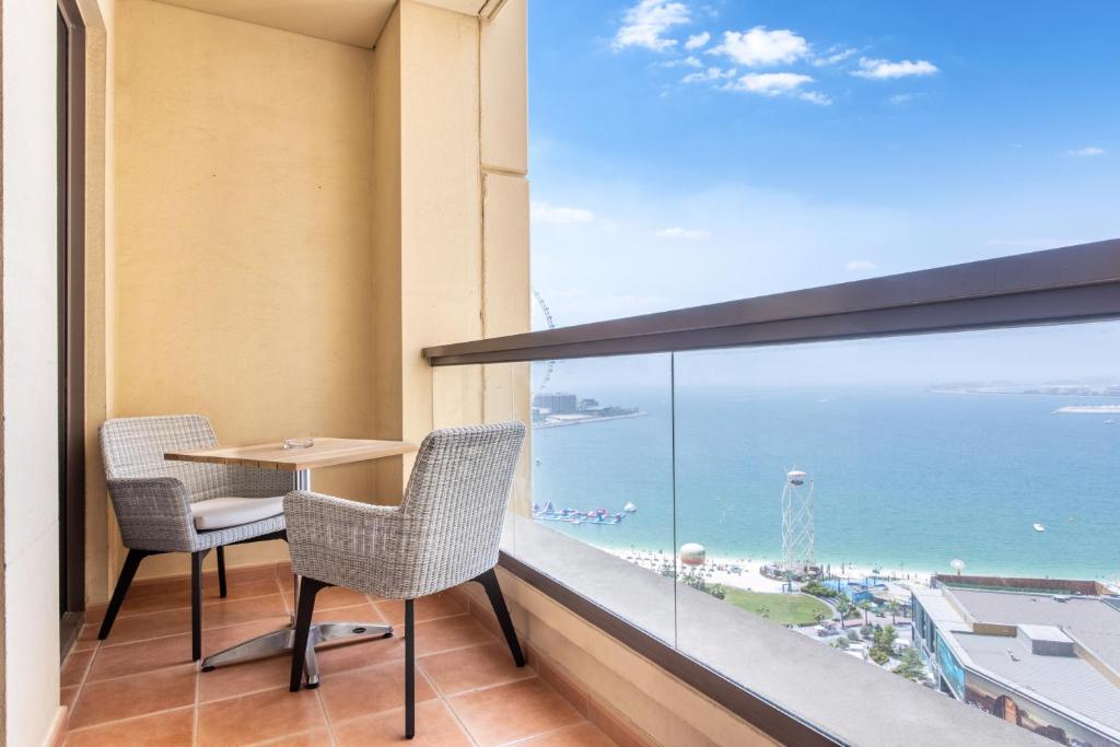balcón con mesa, sillas y vistas al océano en Icon Casa Living - Rimal 3 Residence - JBR, en Dubái
