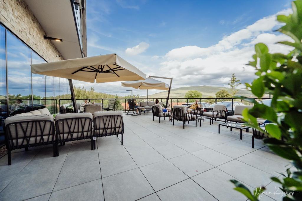 taras ze stołami, krzesłami i parasolem w obiekcie Elements Hotel&Spa w Świeradowie Zdroju