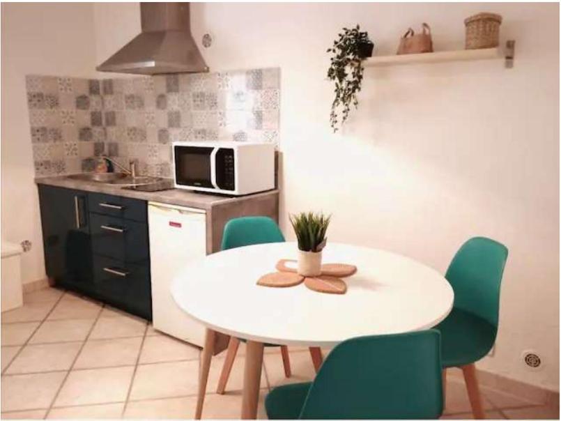 uma cozinha com uma mesa branca e cadeiras verdes em Appartement indépendant, Hyper-centre pittoresque em Salon-de-Provence