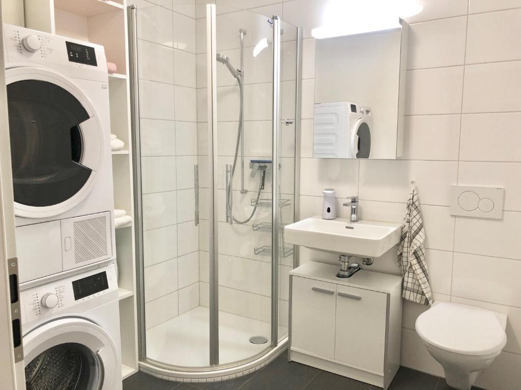 a bathroom with a shower and a sink and a washing machine at Gemuetliche 2 Zimmer Wohnung mit Gartensitzplatz in Fällanden