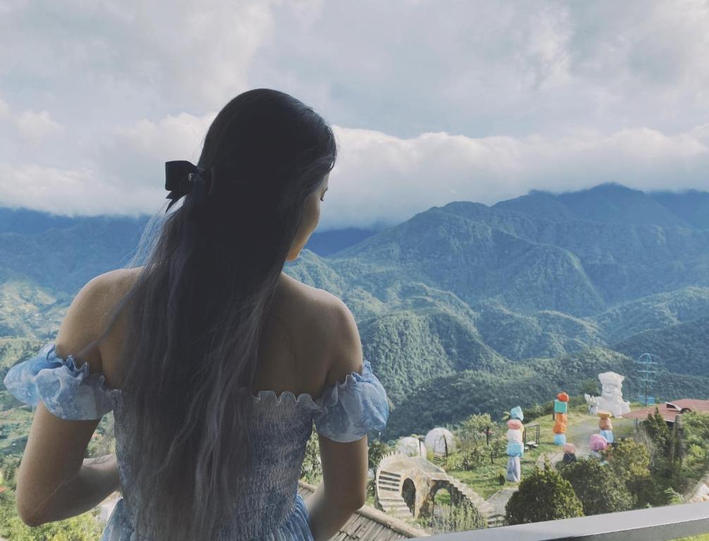 Una mujer parada en un balcón con vistas a las montañas en Villa Sa Pa en Sa Pa
