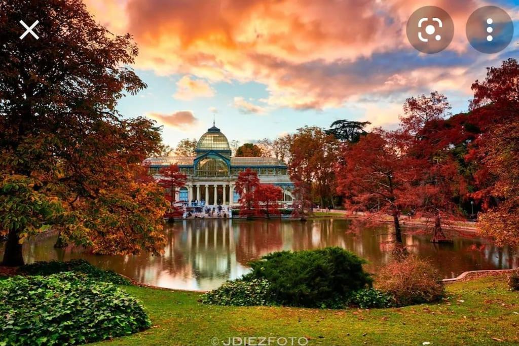 un grand bâtiment avec un étang en face dans l'établissement Parque El Retiro Madrid, à Madrid