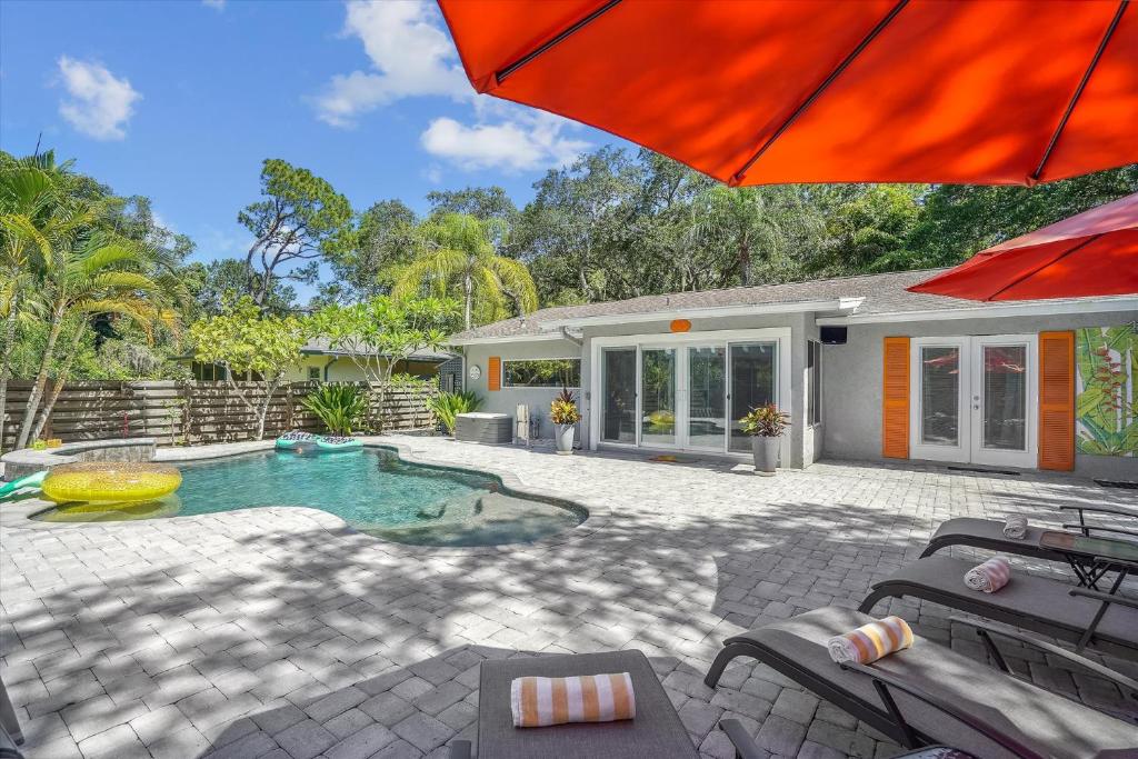a house with a swimming pool and an umbrella at Sapphire Shores - Sarasota Bungalow w/ Heated Pool and Backyard Oasis in Sarasota