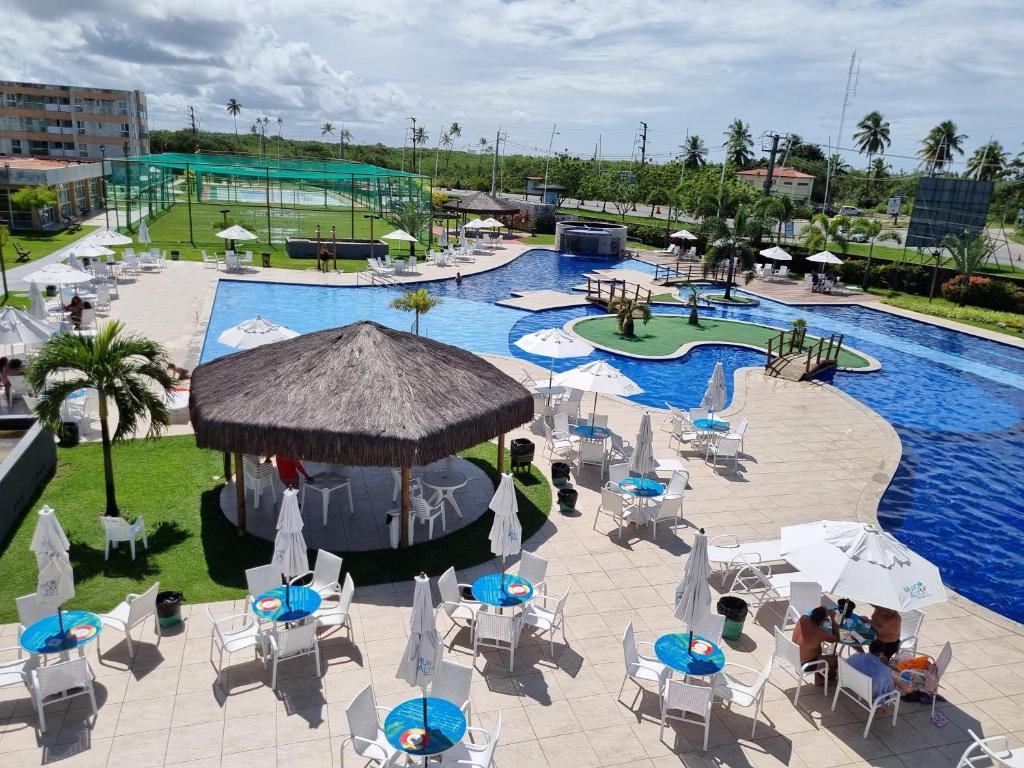 ein Außenpool mit Tischen und Stühlen und ein Swimmingpool in der Unterkunft Flat Sun House Muro Alto - Conforto e Estrutura de Resort in Ipojuca