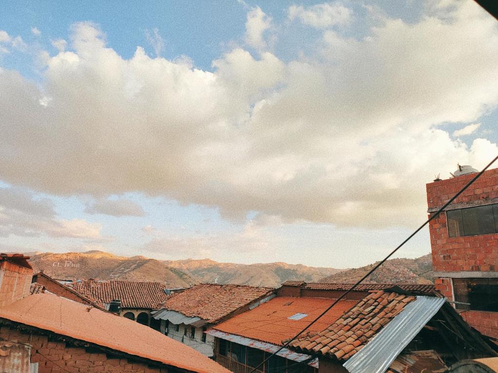 a view of roofs of buildings with mountains in the background at ENEDE HOSTEL in Cusco