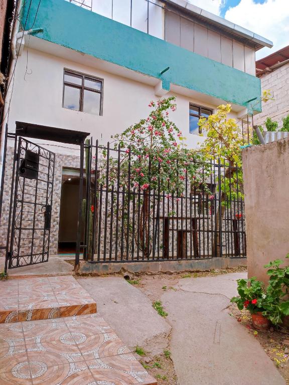 a gate in front of a white building with flowers at ENEDE HOSTEL in Cusco