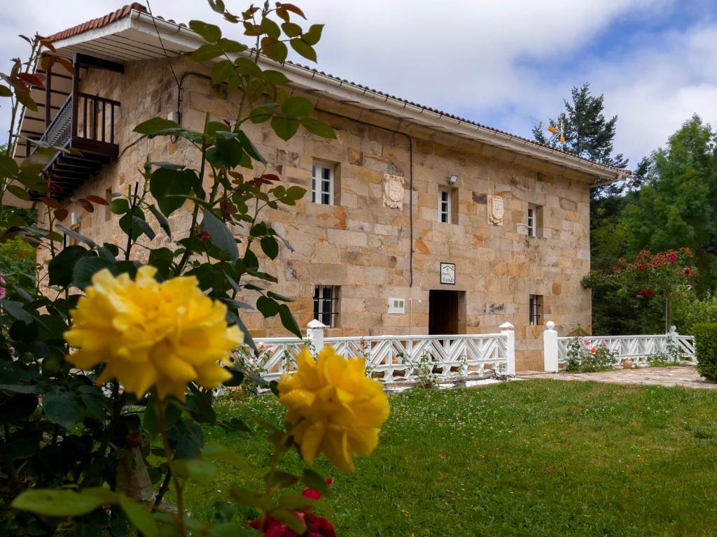 an old stone building with yellow flowers in front of it at Casa Rural Puerto del Escudo in Cilleruelo de Bezana