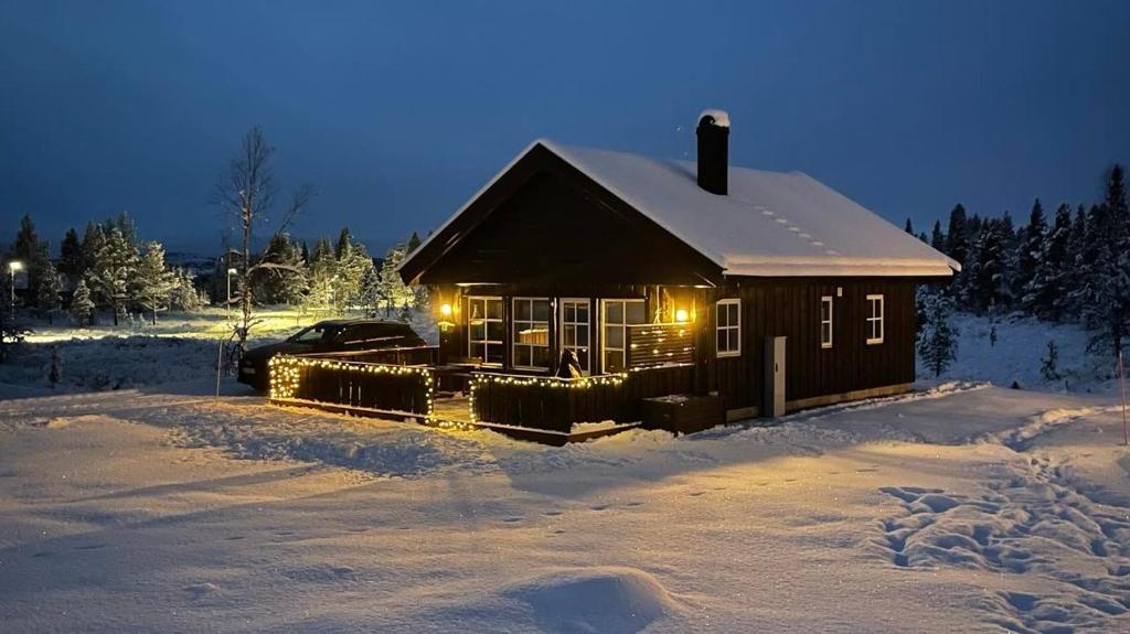 una cabaña en la nieve con luces encendidas en Sanderstølen Hytter, en Sanderstølen