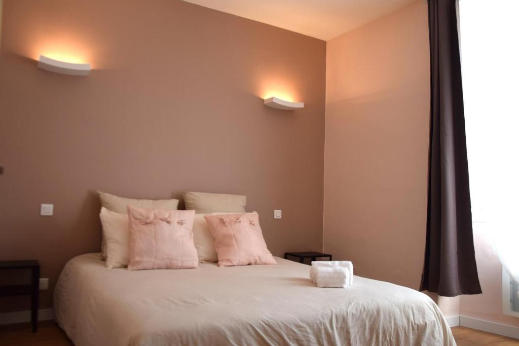 a bedroom with a white bed with pink pillows at LE LYS in Lacrouzette