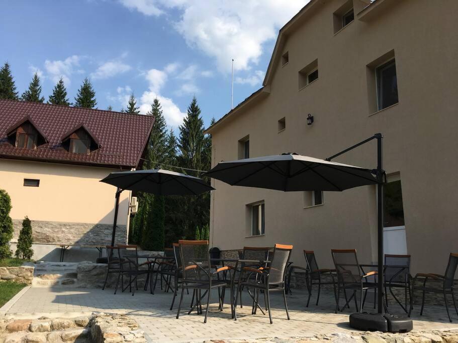 een groep stoelen en tafels met parasols naast een gebouw bij Aleu - Apuseni Mountains in Pietroasa