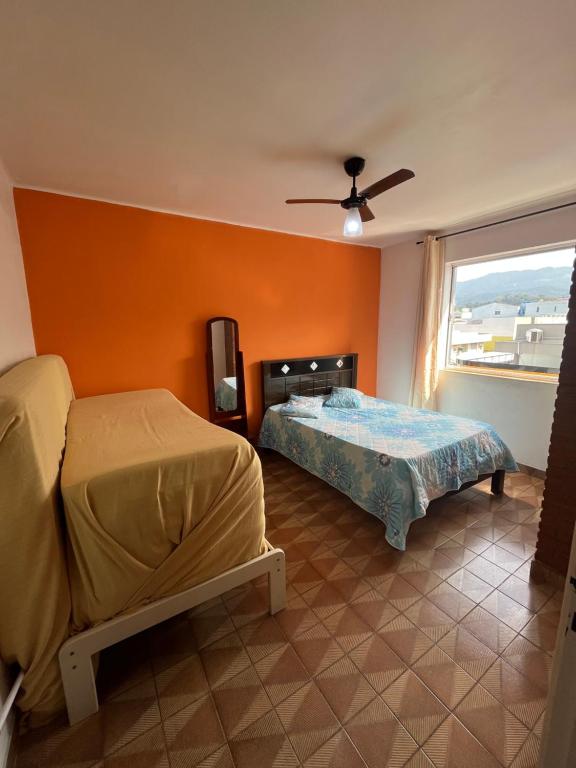 a bedroom with two beds and a window at Apartamento no CENTRO de Caraguatatuba. in Caraguatatuba