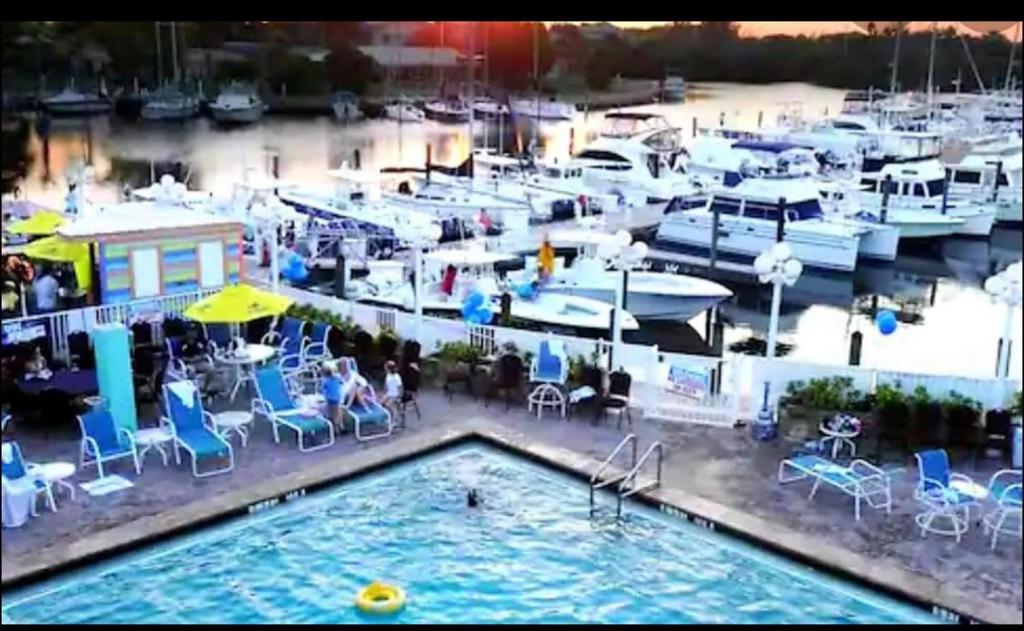una piscina con mesas, sillas y barcos en un puerto deportivo en Remodeled, Huge Pool, Tiki Bar & Grill, Quiet Room, en Sarasota
