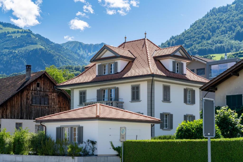 une grande maison blanche avec un toit carrelé dans l'établissement Verena's Boutique Villa au lac, à Sachseln