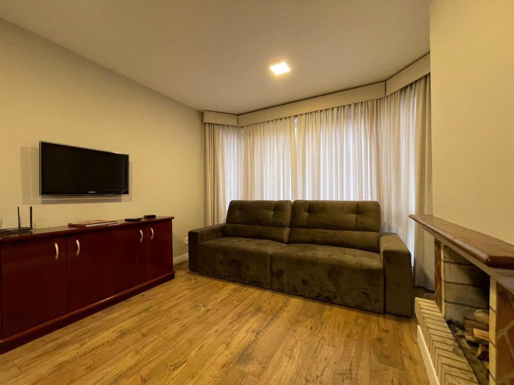a living room with a couch and a flat screen tv at Apartamento a 100m da Rua Coberta in Gramado