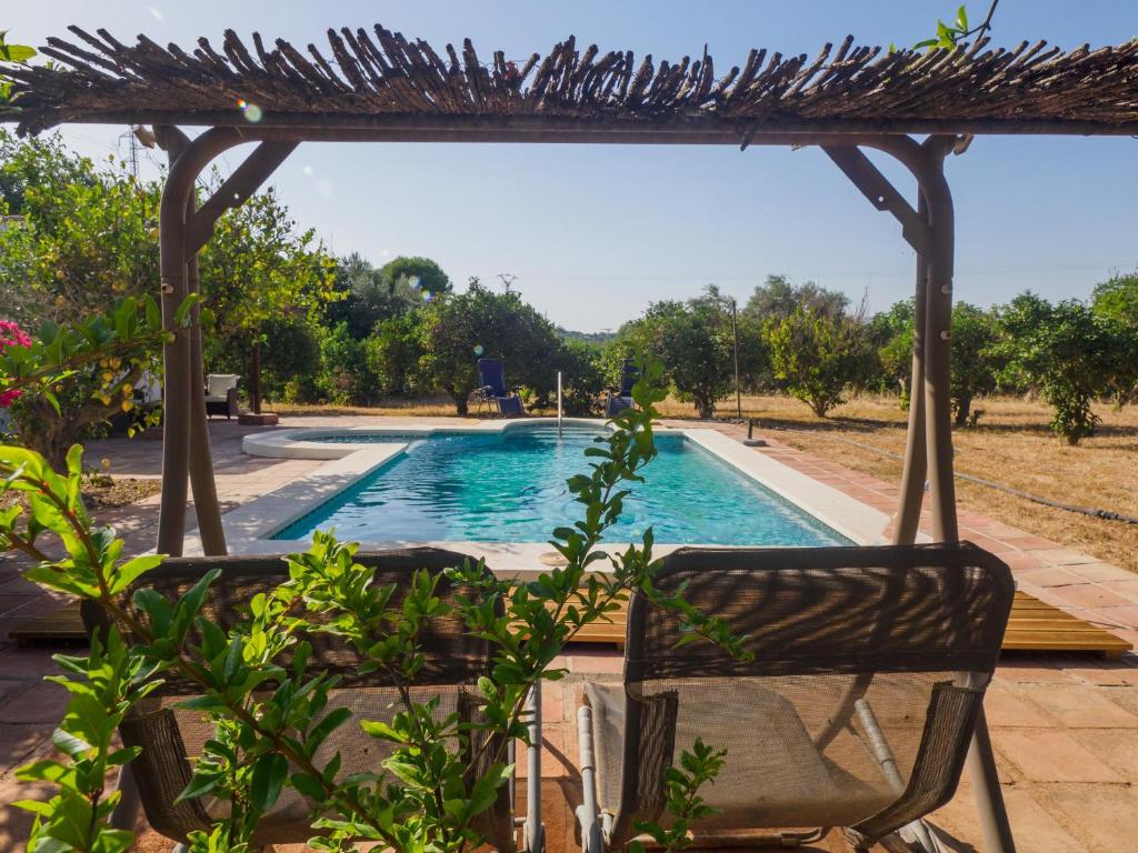 a swimming pool with a chair and a pergola at Cubo's Cortijo La Bolina in Villafranco de Guadalhorce