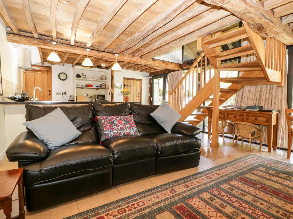 a leather couch in a living room with a wooden ceiling at Tinkley Cottage in Nymphsfield