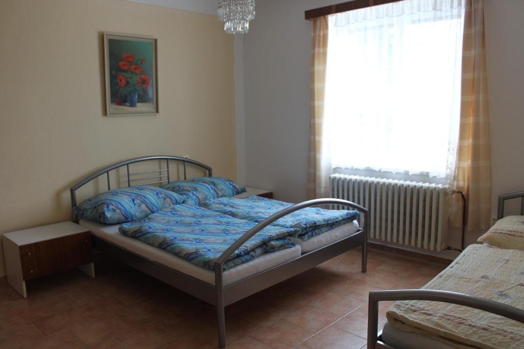 a bedroom with a bed with blue sheets and a window at Domek u lesa in Bítov