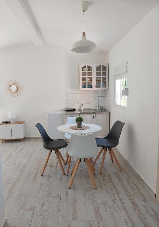 a white kitchen with a white table and chairs at Apartmani.Sutomore in Sutomore