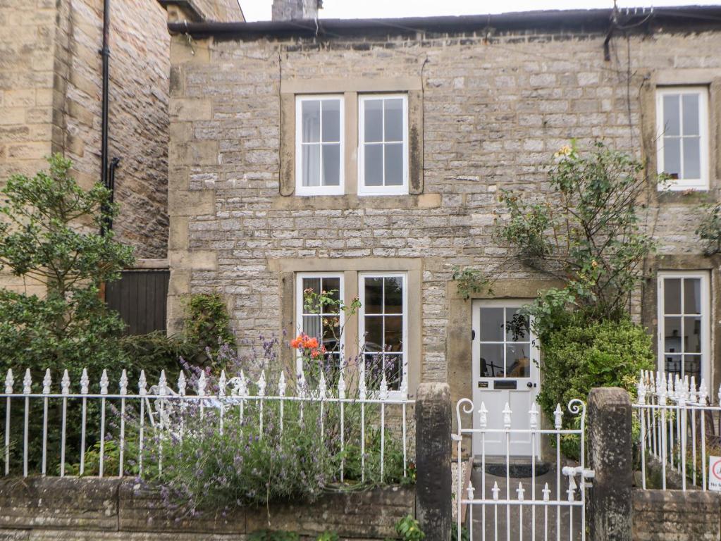 an old stone house with a white fence at White Swan Cottage in Bakewell