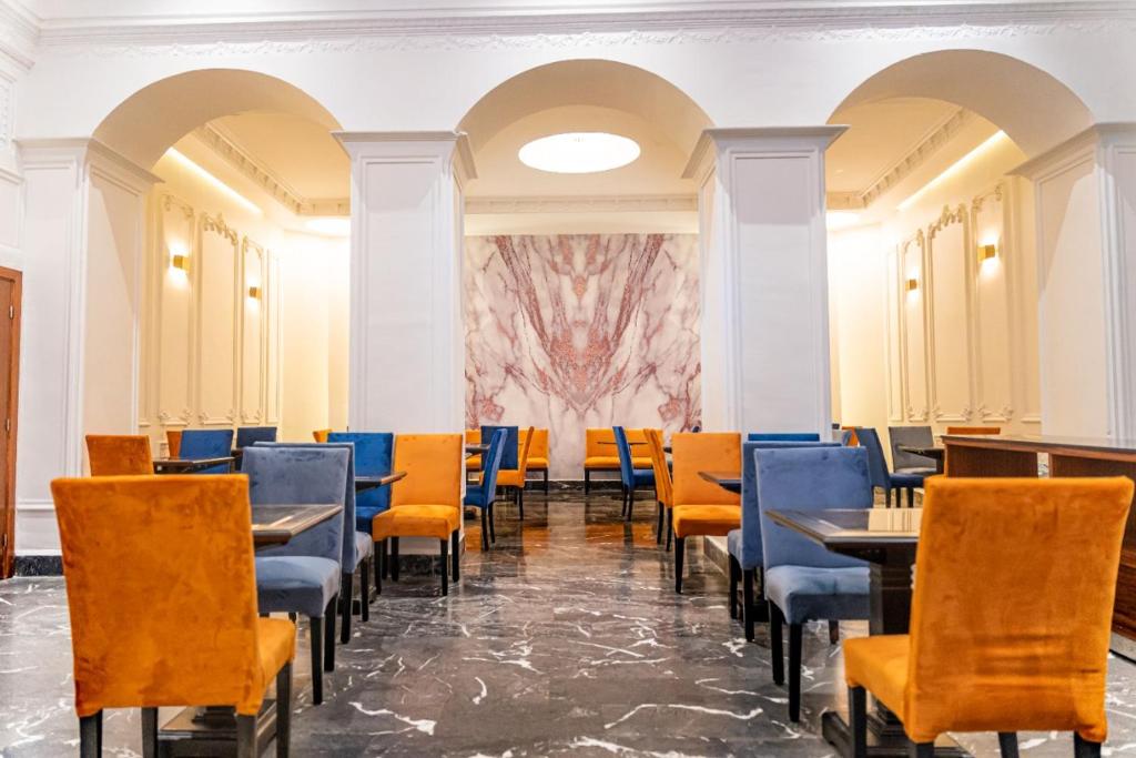 a dining room with tables and chairs and a painting on the wall at Hotel Majestic in Casablanca