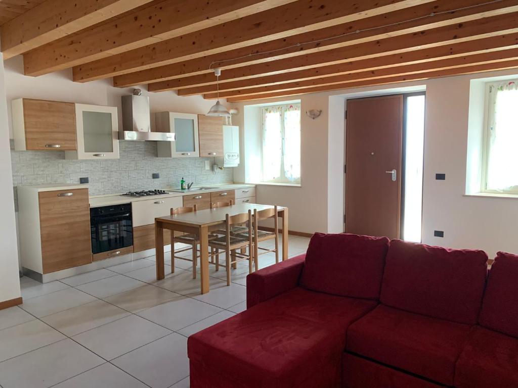 uma sala de estar com um sofá vermelho e uma cozinha em LA CASA DI MARTINA em Castelnuovo del Garda