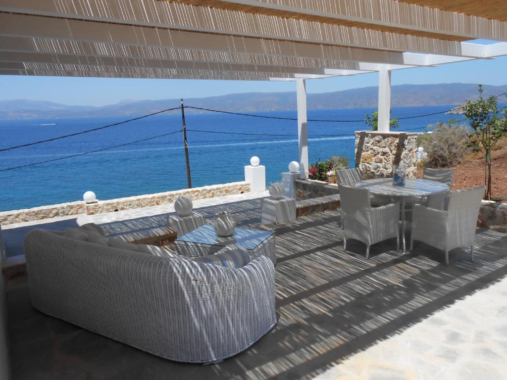 a patio with a table and chairs and the ocean at HydraVista (Lily) in Hydra