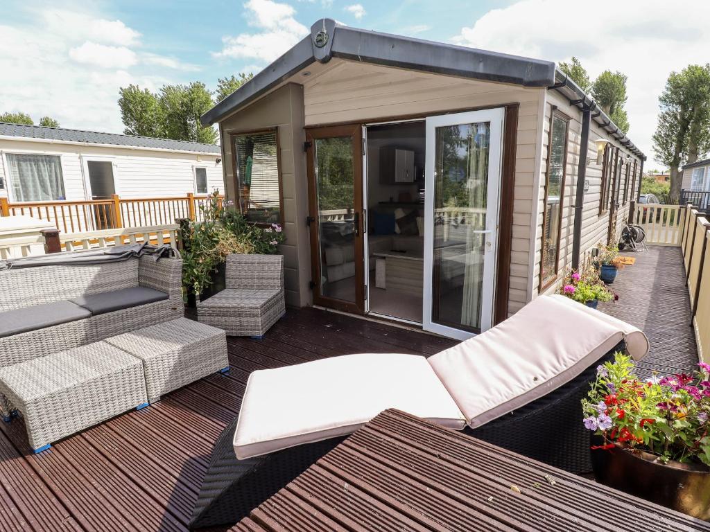 a tiny house with a deck with chairs and a patio at 19 The Brambles in Humberston