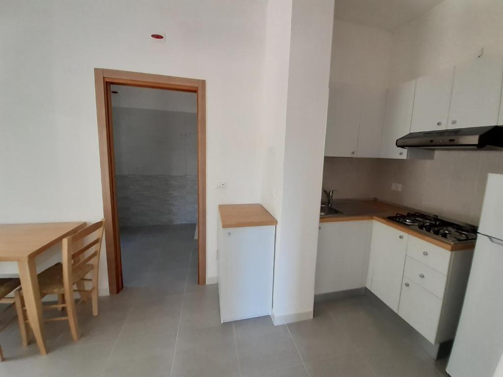 a kitchen with white cabinets and a table and a door at La Marina Bay in Vieste