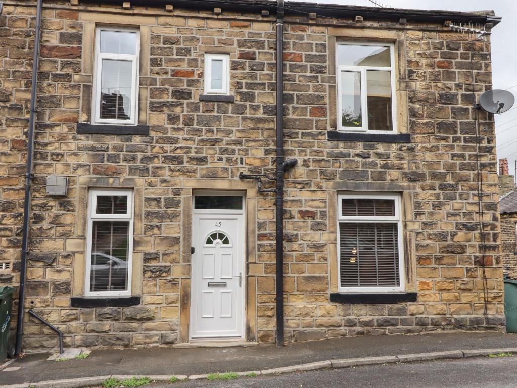 a brick building with a white door and windows at 45 Prince Street in Keighley