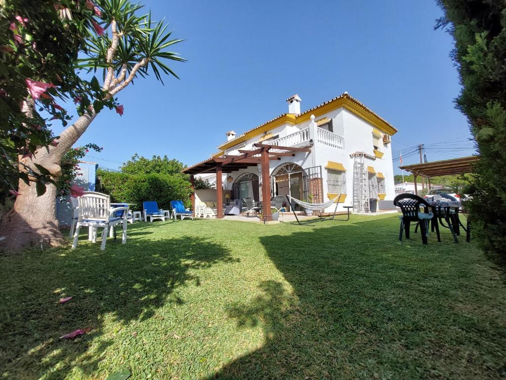 una casa con un cortile con sedie e un'altalena di Beach and Golf House La Cala de Mijas a La Cala de Mijas
