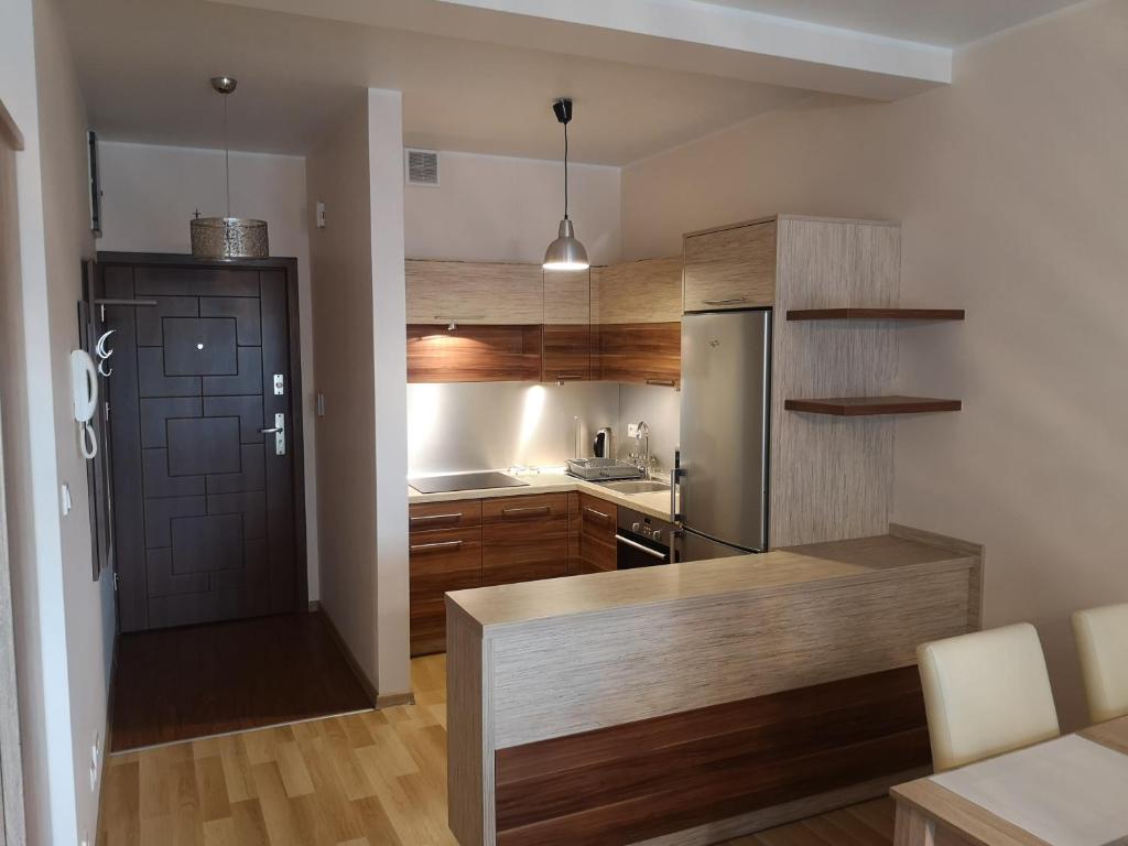 kuchnia z drewnianymi szafkami i lodówką ze stali nierdzewnej w obiekcie Apartament Marzenie 11 - Opole w mieście Opole