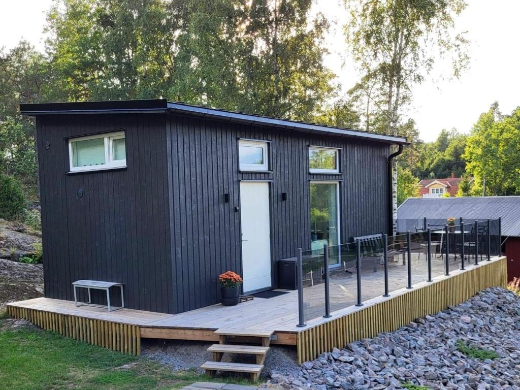 a black tiny house on a wooden deck at Cabin in the woods, close to Lake Mälaren in Eskilstuna